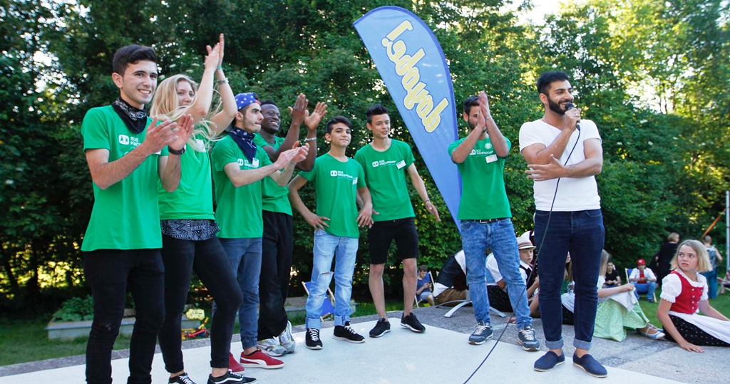 Onur Bakis mit einer Gruppe Jugendlicher auf einer Bühne